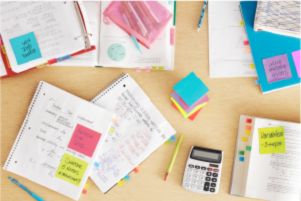 Cuadernos con notas, calculadora y lápiz amarillo.
