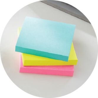 Blocs de notas azul, amarillo y rosa apilados.
